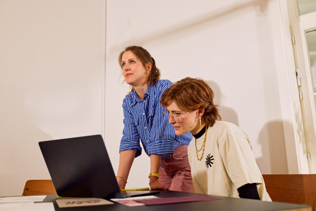 Dana und Kim von ooniyo stehen am Computer und besprechen neue Markenentwicklungskonzepte