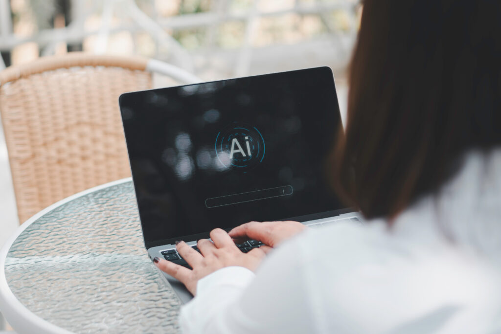 Eine Frau sitzt an einem Café-Tisch an ihrem Laptop und arbeitet mit Ai