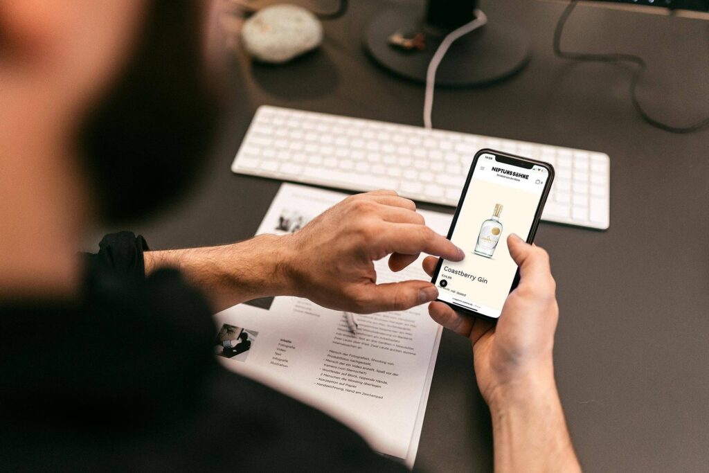 e-commerce Vergleich auf einem Handy - ein Mann hält das Handy in der Hand und schaut auf den Bildschirm