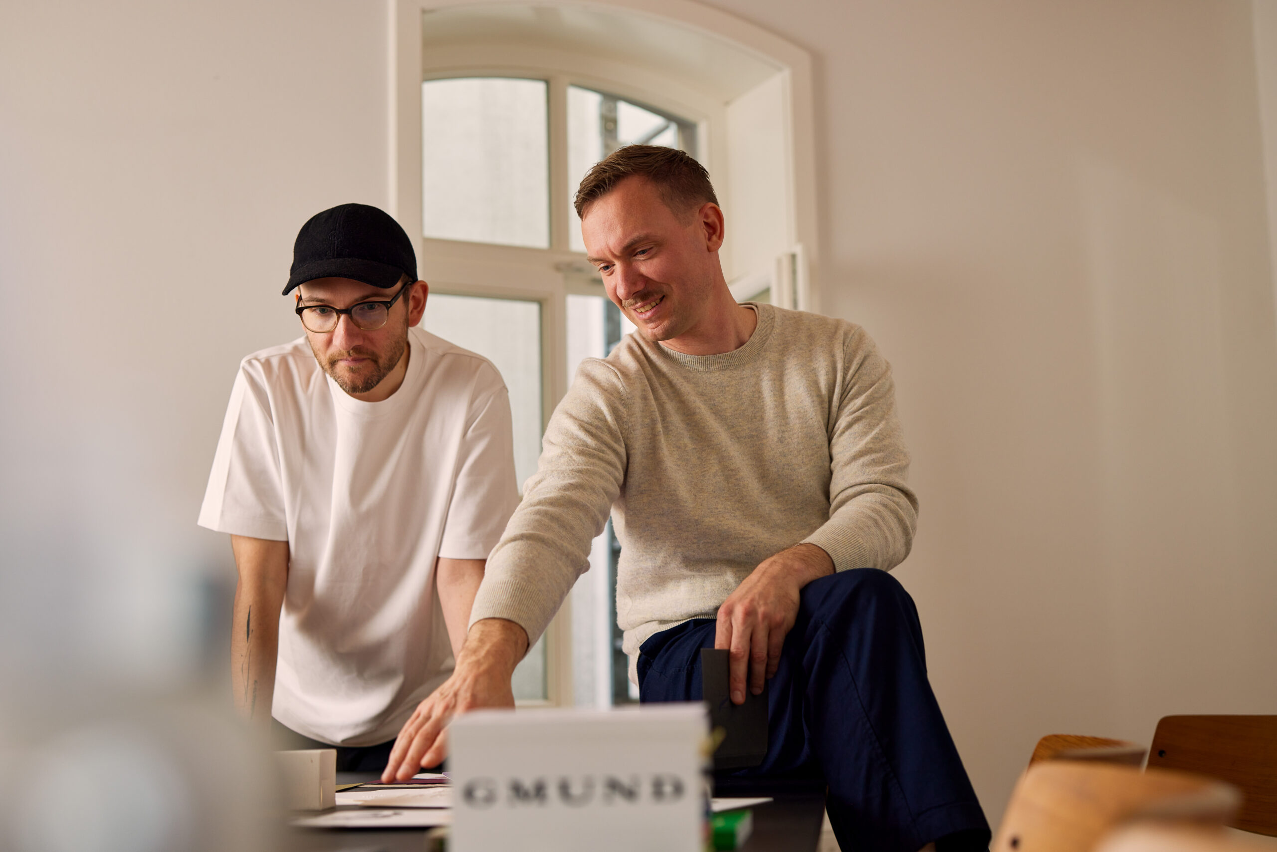 Niklas und Benjamin von ooniyo besprechen am Tisch die Materialien für ein neues Brand Experience Projekt