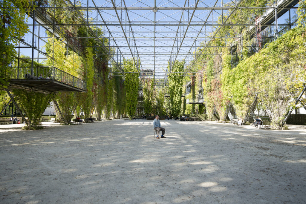 Ein Mann sitzt auf einem Stuhl in einer Halle mit vielen Pflanzen | Neue Räume Zürich 2026